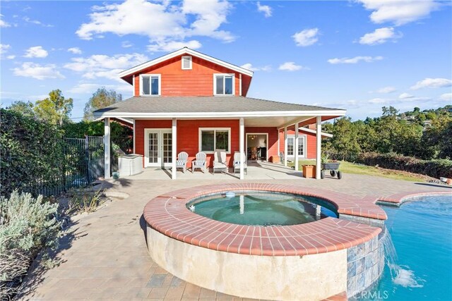 back of property featuring pool water feature, a pool with hot tub, a patio area, and french doors