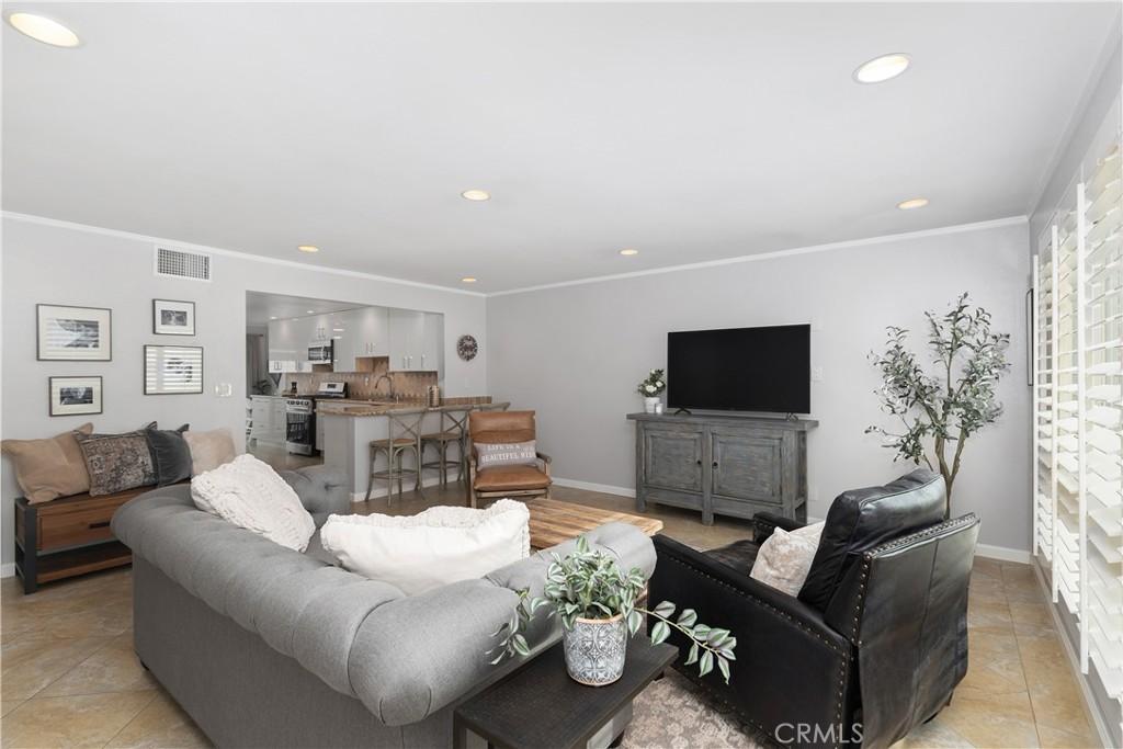 living area featuring recessed lighting, baseboards, visible vents, and ornamental molding