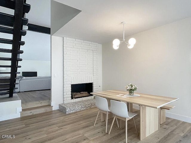 dining area featuring a fireplace, a chandelier, and light hardwood / wood-style floors