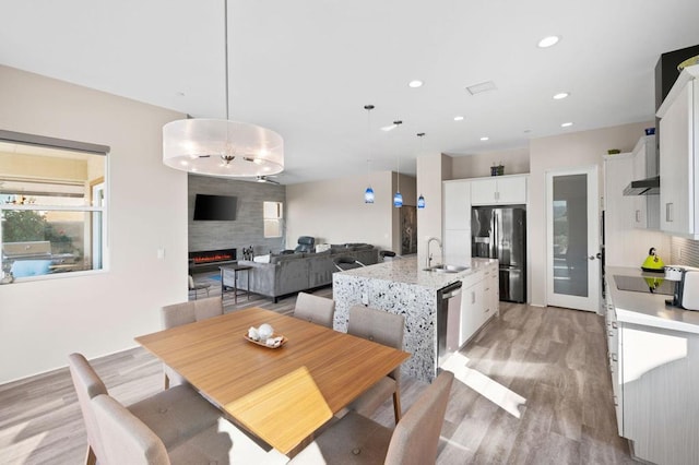 dining space featuring sink, light hardwood / wood-style floors, and a large fireplace