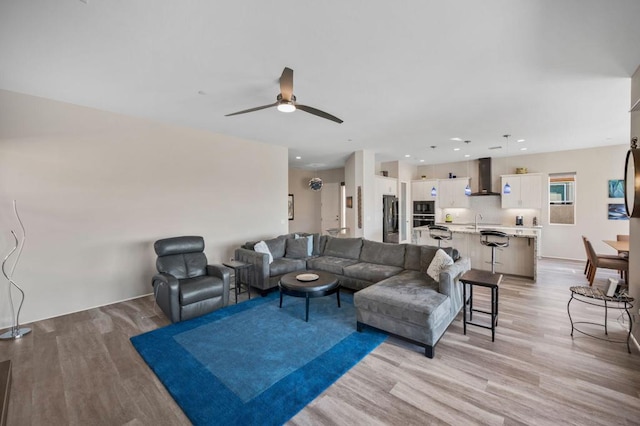 living room with sink, light hardwood / wood-style floors, and ceiling fan