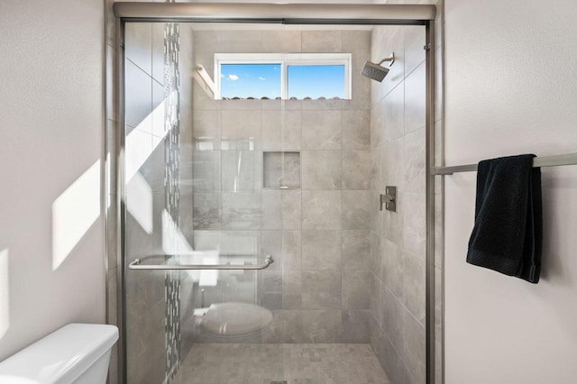 bathroom featuring a shower with shower door and toilet