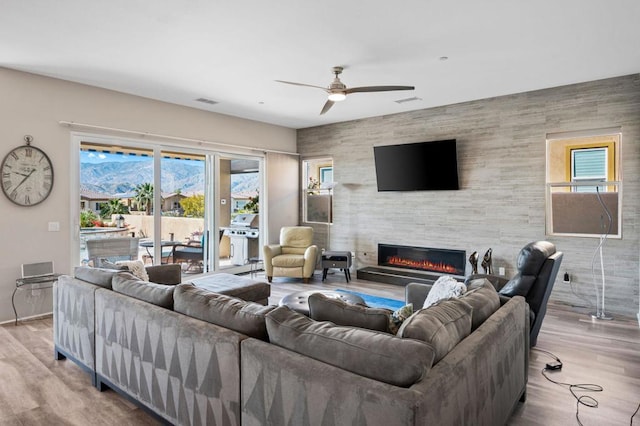 living room with hardwood / wood-style flooring, a tile fireplace, and ceiling fan