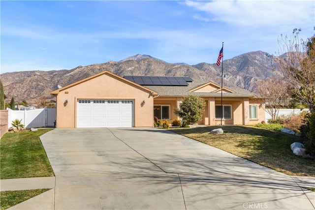 ranch-style home featuring a mountain view, a garage, a front lawn, and solar panels