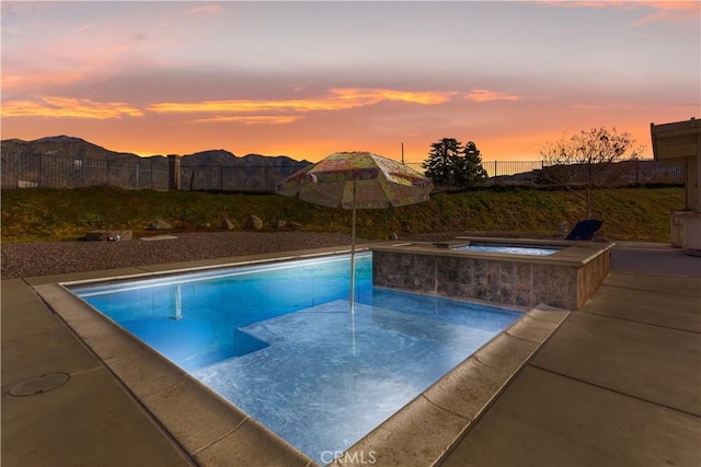 pool at dusk featuring an in ground hot tub