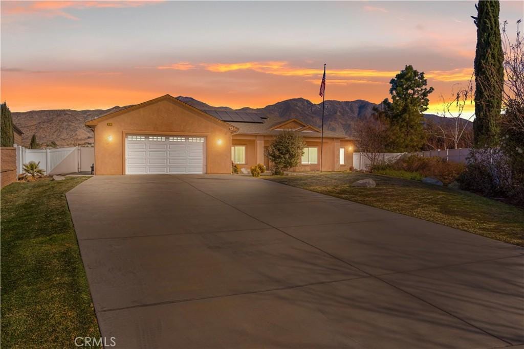 view of front of home with a garage, a mountain view, solar panels, and a lawn