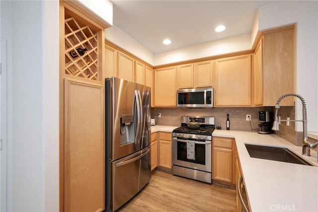 kitchen with light brown cabinetry, sink, stainless steel appliances, light hardwood / wood-style floors, and backsplash