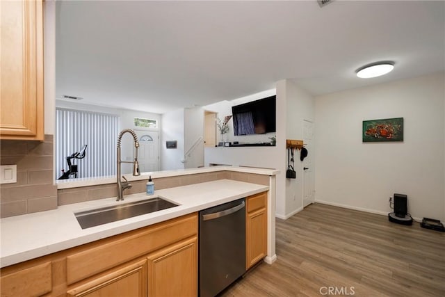 kitchen with sink, backsplash, stainless steel dishwasher, light brown cabinets, and light wood-type flooring