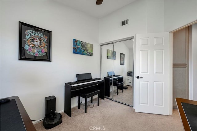 misc room featuring light colored carpet, ceiling fan, and a high ceiling