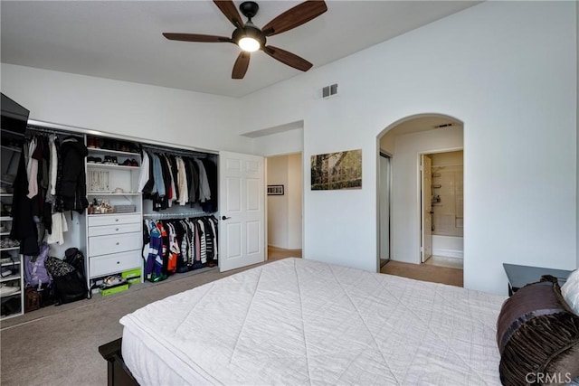 carpeted bedroom featuring lofted ceiling, connected bathroom, ceiling fan, and a closet