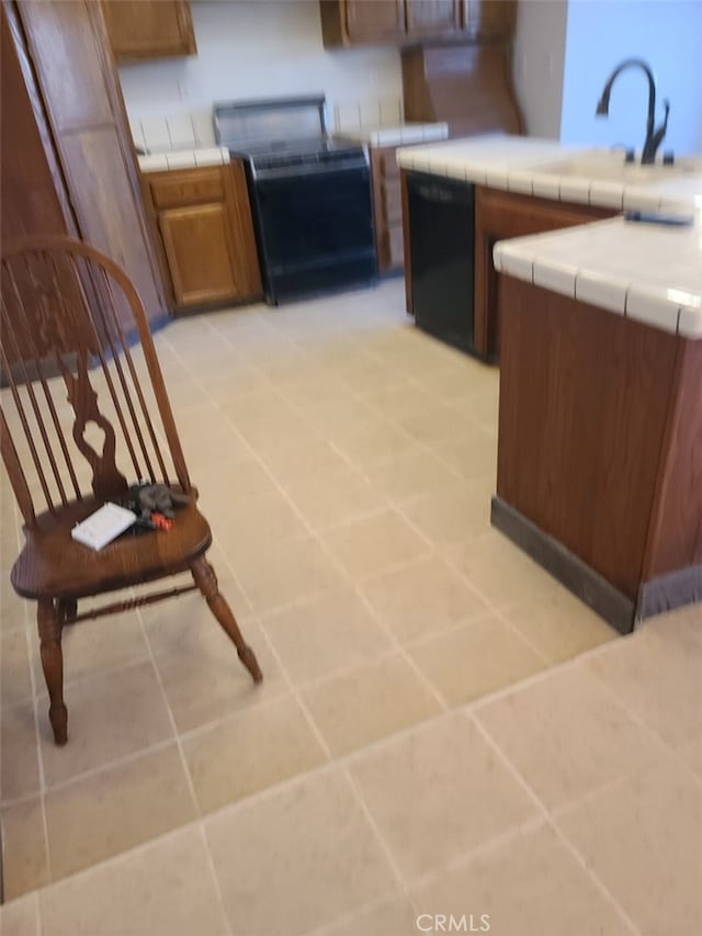 kitchen with stove, light tile patterned floors, tile counters, and dishwasher