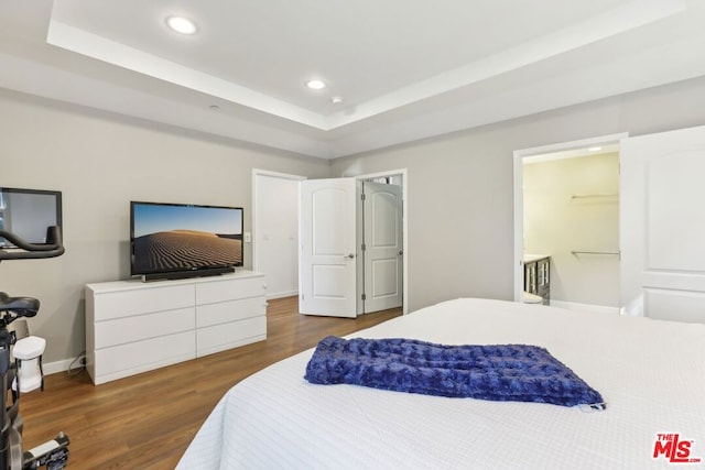 bedroom with dark hardwood / wood-style flooring and a tray ceiling