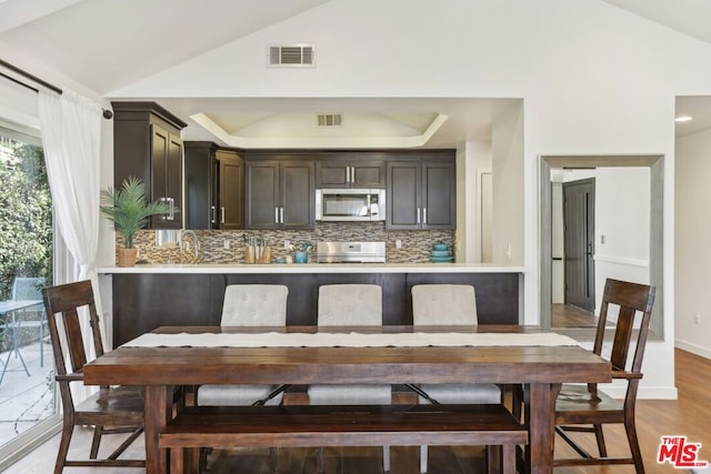 kitchen featuring lofted ceiling, light wood-type flooring, decorative backsplash, and stove