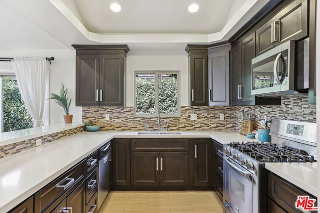 kitchen featuring stainless steel appliances, sink, kitchen peninsula, and decorative backsplash