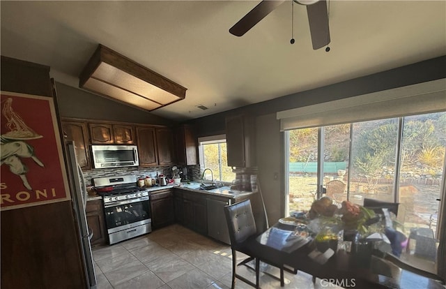 kitchen featuring vaulted ceiling, tasteful backsplash, sink, stainless steel appliances, and dark brown cabinets