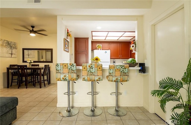 kitchen with white refrigerator, ceiling fan, light tile patterned flooring, and kitchen peninsula