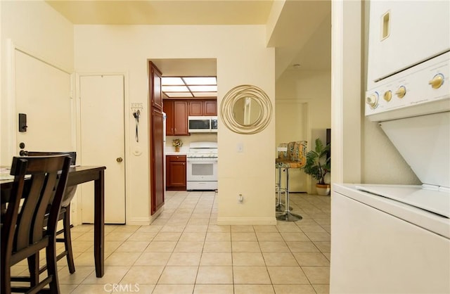 kitchen featuring light tile patterned floors, stacked washer / dryer, and range