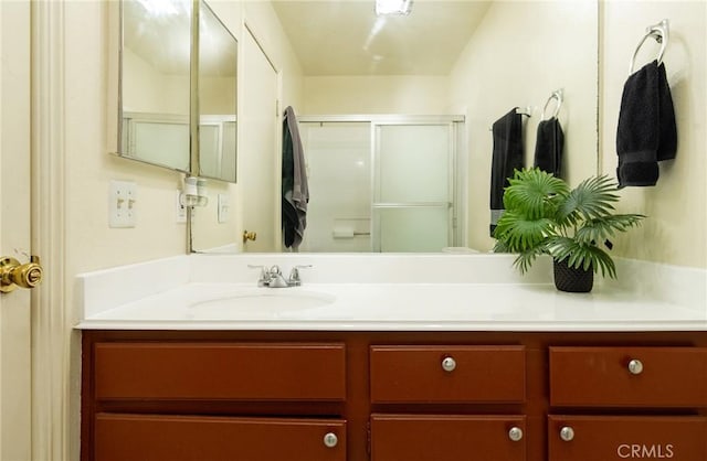 bathroom featuring a shower with door and vanity