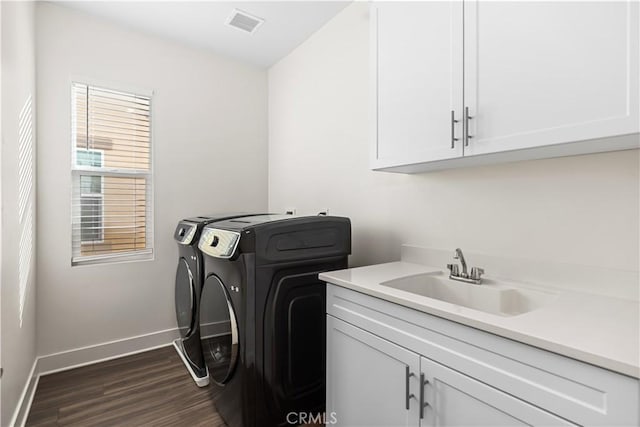 laundry area featuring cabinets, washer and dryer, sink, and dark wood-type flooring