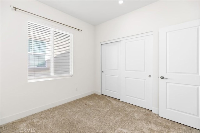 unfurnished bedroom with light colored carpet and a closet