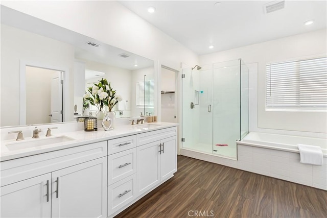 bathroom with wood-type flooring, shower with separate bathtub, and vanity