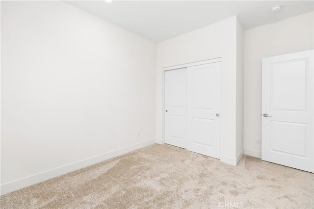 unfurnished bedroom featuring light carpet and a closet