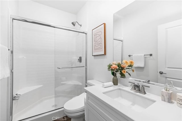 bathroom featuring vanity, a shower with shower door, and toilet