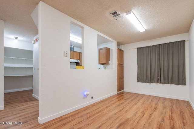 spare room featuring a textured ceiling and light wood-type flooring