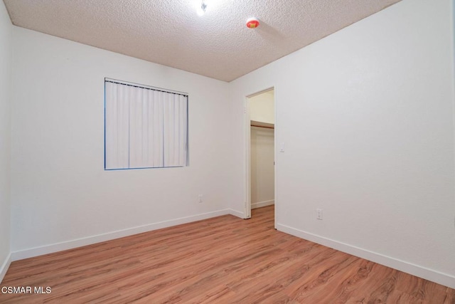 unfurnished room with light hardwood / wood-style floors and a textured ceiling