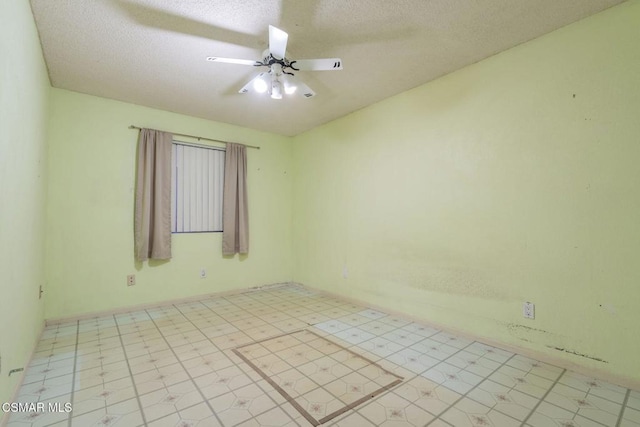 unfurnished room with ceiling fan and a textured ceiling