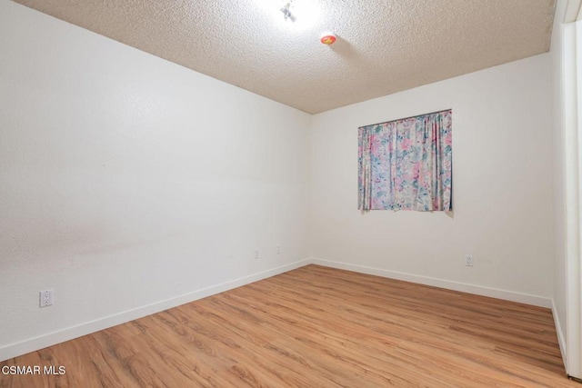 unfurnished room featuring light hardwood / wood-style flooring and a textured ceiling