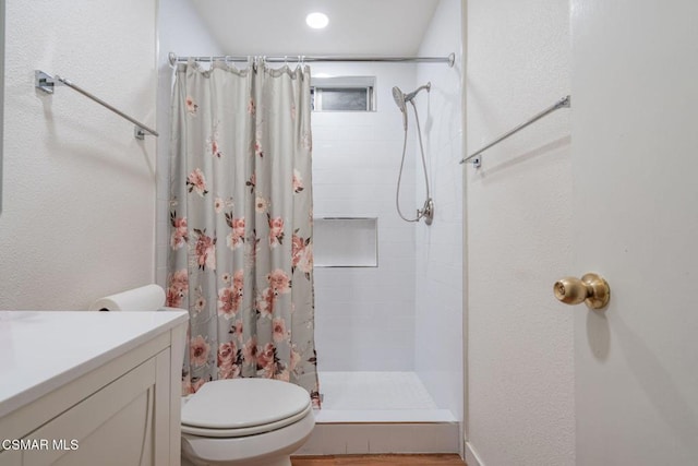 bathroom with walk in shower, vanity, and toilet