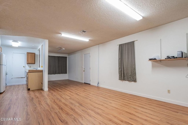 spare room featuring a textured ceiling and light hardwood / wood-style floors