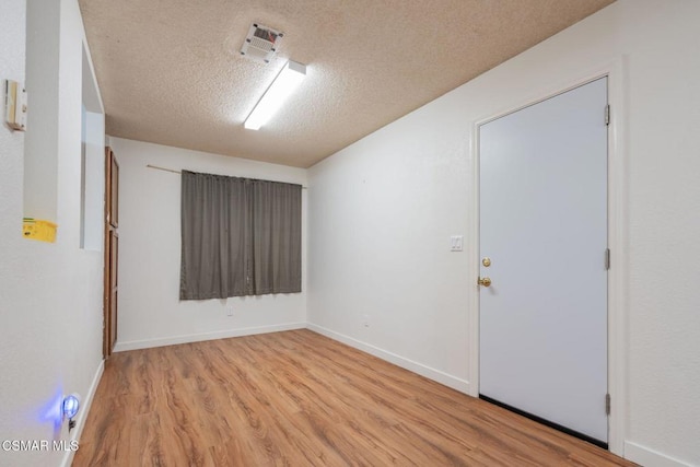 empty room featuring a textured ceiling and light hardwood / wood-style flooring