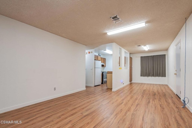 unfurnished living room featuring light hardwood / wood-style flooring and a textured ceiling