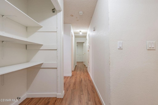 corridor featuring a textured ceiling and light hardwood / wood-style flooring