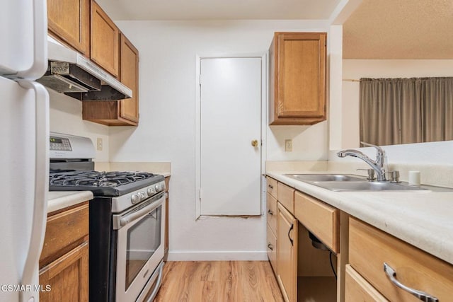 kitchen with fridge, light hardwood / wood-style floors, sink, and stainless steel gas stove