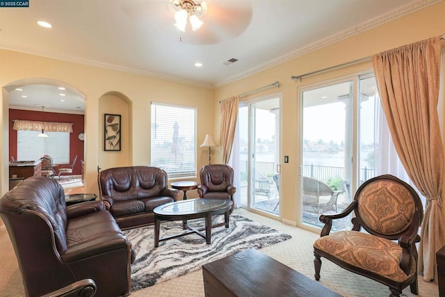 carpeted living room with ceiling fan and ornamental molding