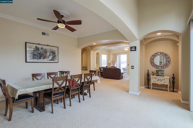 carpeted dining space featuring crown molding and ceiling fan