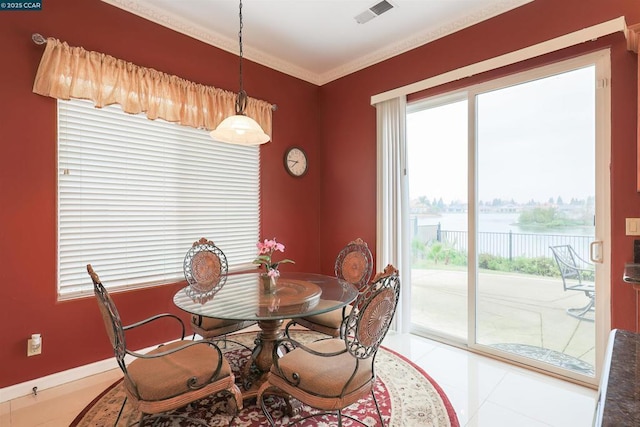 dining area featuring a water view, ornamental molding, and light tile patterned floors