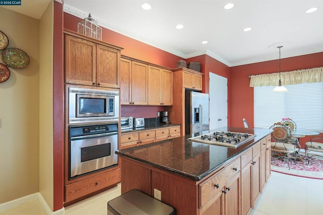 kitchen with pendant lighting, appliances with stainless steel finishes, dark stone countertops, a center island, and ornamental molding