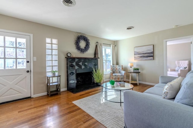 living room featuring a tiled fireplace and hardwood / wood-style floors