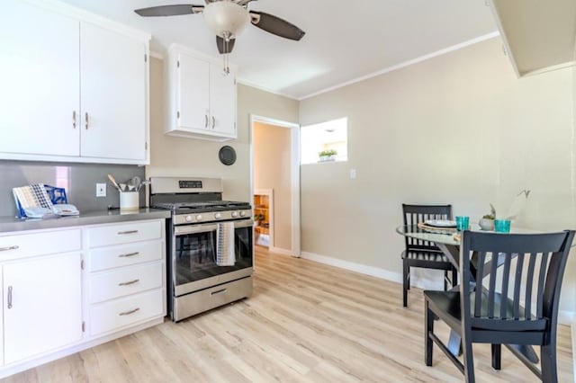 kitchen featuring stainless steel gas stove, white cabinets, ceiling fan, light hardwood / wood-style floors, and crown molding