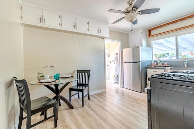 kitchen with stainless steel refrigerator, light wood-type flooring, range with gas cooktop, and white cabinets