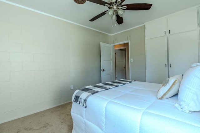 carpeted bedroom with ornamental molding, ceiling fan, and a closet