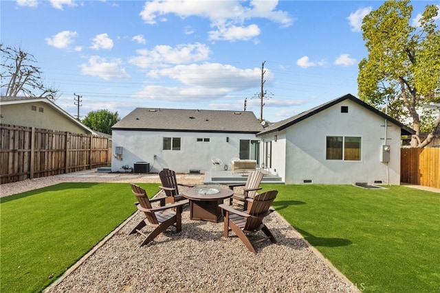 rear view of house with cooling unit, a yard, and a fire pit