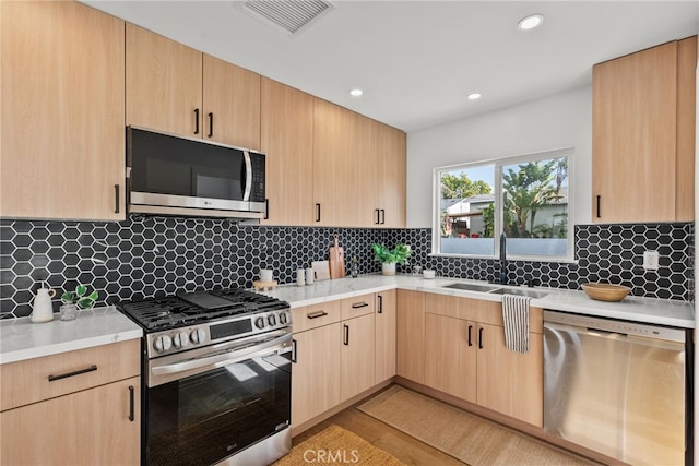 kitchen featuring stainless steel appliances, tasteful backsplash, sink, and light brown cabinetry