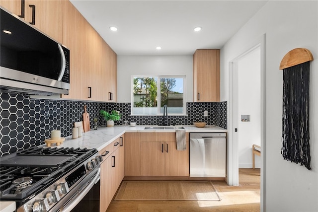 kitchen with sink, light brown cabinets, stainless steel appliances, light stone countertops, and decorative backsplash