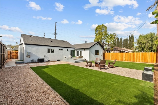 rear view of property featuring cooling unit, a fire pit, a patio area, and a lawn