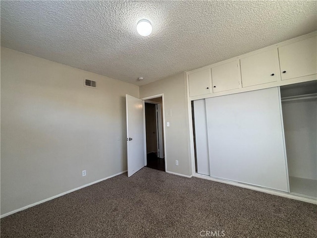 unfurnished bedroom featuring dark carpet, a closet, and a textured ceiling